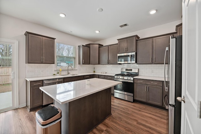 kitchen featuring sink, dark hardwood / wood-style floors, appliances with stainless steel finishes, plenty of natural light, and a kitchen island