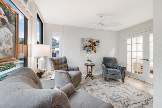 living room with light hardwood / wood-style floors, ceiling fan, and french doors