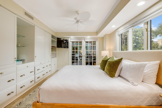 bedroom featuring ceiling fan, hardwood / wood-style floors, crown molding, and french doors