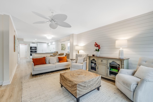 living room with light wood-type flooring, wooden walls, and ceiling fan