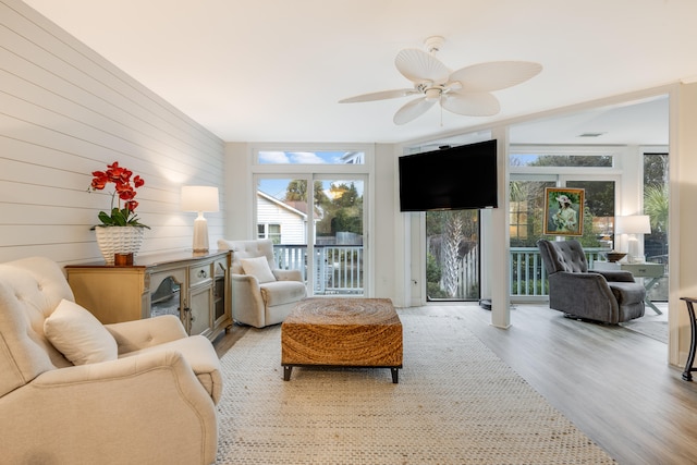 living room featuring wood walls, light hardwood / wood-style floors, and ceiling fan