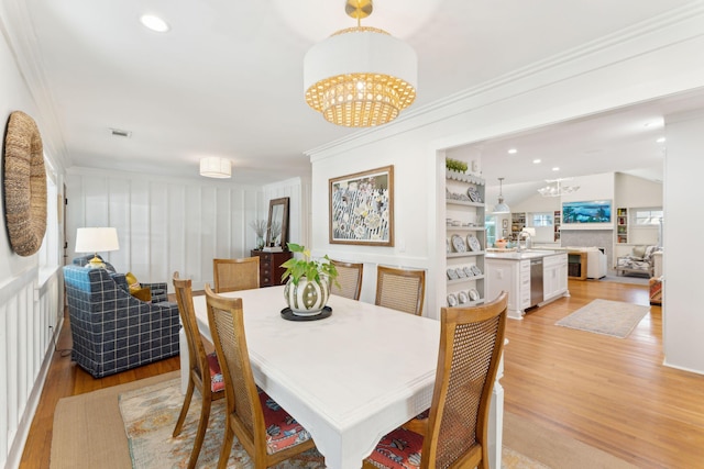 dining area with a notable chandelier, crown molding, light hardwood / wood-style floors, and sink