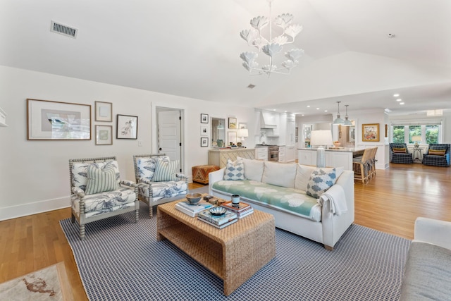 living room featuring wood-type flooring, a chandelier, and vaulted ceiling