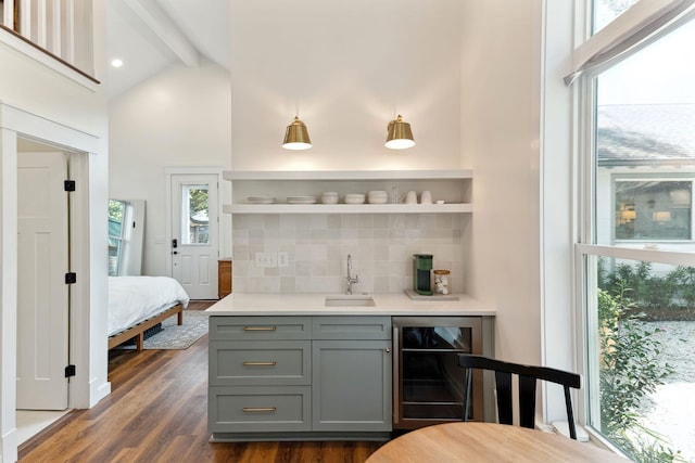 bar featuring tasteful backsplash, sink, gray cabinetry, beverage cooler, and dark wood-type flooring