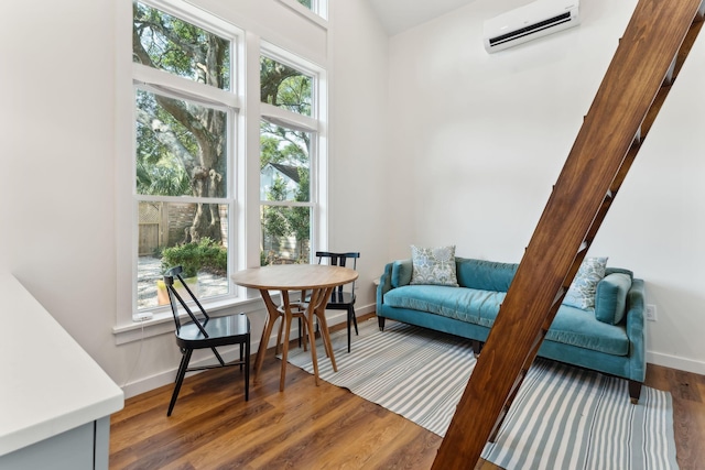 living area with a wall unit AC and dark hardwood / wood-style floors