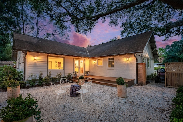 back house at dusk featuring a patio and a deck