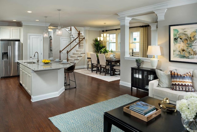 kitchen with sink, white cabinets, hanging light fixtures, light stone counters, and stainless steel refrigerator with ice dispenser