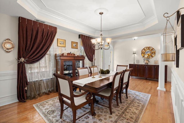 dining space with visible vents, ornamental molding, a tray ceiling, light wood-style floors, and a chandelier