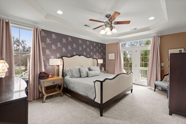 bedroom with multiple windows, light colored carpet, a tray ceiling, and access to outside