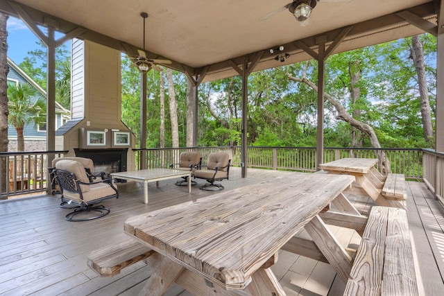 wooden deck with a fireplace and a ceiling fan