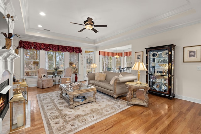 living area with visible vents, a raised ceiling, light wood-style flooring, and a tiled fireplace