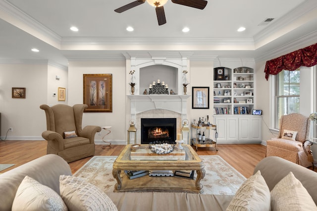 living area with a tray ceiling, wood finished floors, and crown molding