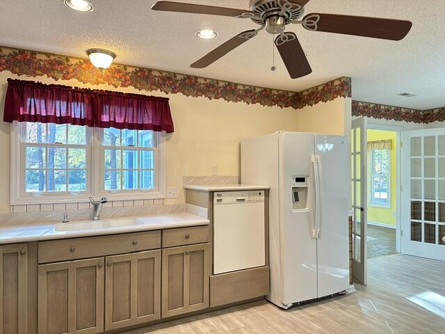 kitchen with white appliances, light wood-style floors, light countertops, and a sink