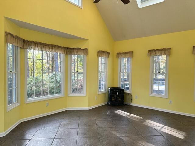209 Myrtlewood Dr, Santee, SC 29142 - spare room with a ceiling fan, a wood stove, baseboards, tile patterned floors, and high vaulted ceiling