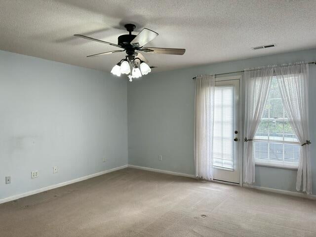 unfurnished room featuring baseboards, visible vents, a ceiling fan, light colored carpet, and a textured ceiling