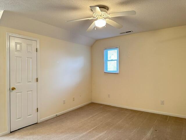 209 Myrtlewood Dr, Santee, SC 29142 - empty room featuring a textured ceiling, light carpet, a ceiling fan, baseboards, and vaulted ceiling