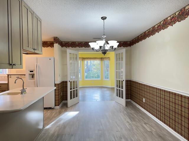 kitchen with a wainscoted wall, light countertops, french doors, and a sink