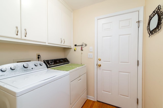 laundry area featuring washing machine and clothes dryer, light hardwood / wood-style flooring, and cabinets