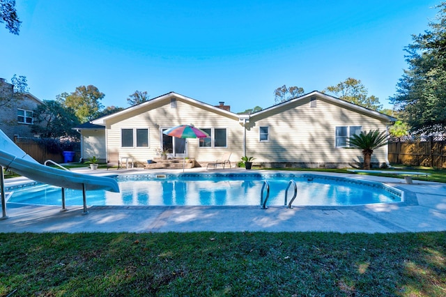 view of swimming pool with a lawn, a water slide, and a patio