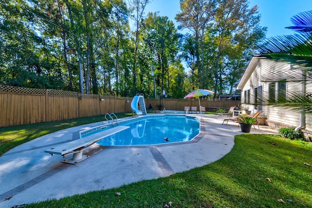 view of swimming pool with a yard, a diving board, a patio area, and a water slide