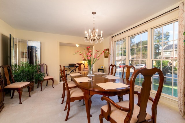 carpeted dining area with an inviting chandelier