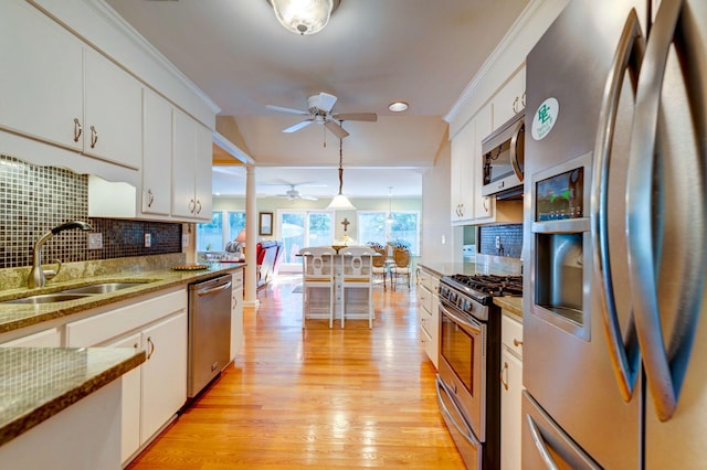 kitchen featuring sink, stainless steel appliances, pendant lighting, decorative backsplash, and white cabinets