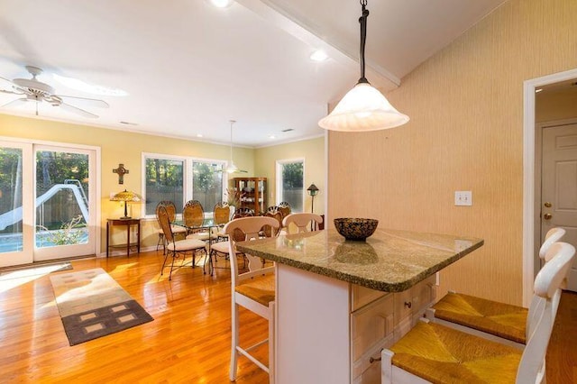 kitchen featuring a kitchen breakfast bar, light wood-type flooring, hanging light fixtures, and ceiling fan