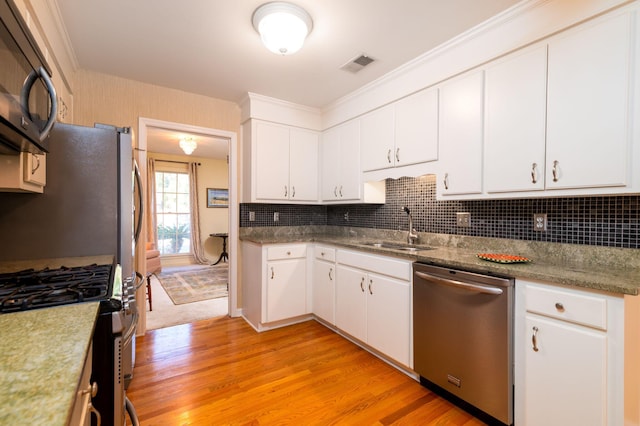 kitchen featuring backsplash, white cabinets, sink, appliances with stainless steel finishes, and light hardwood / wood-style floors