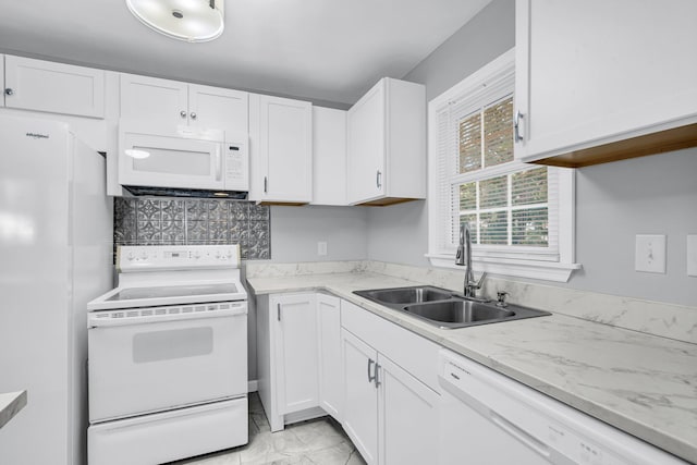 kitchen with white cabinets, light stone countertops, sink, and white appliances