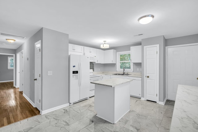 kitchen featuring white cabinets, sink, white appliances, a center island, and light hardwood / wood-style floors