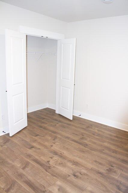 unfurnished bedroom with dark wood-type flooring and a closet