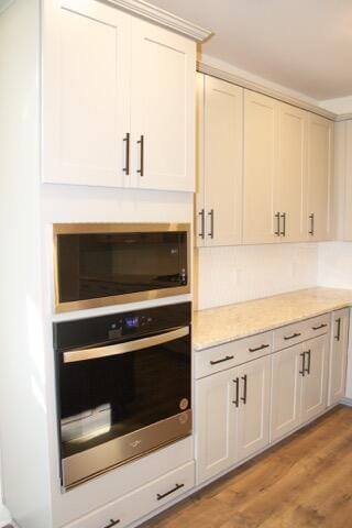 kitchen featuring white cabinets, stainless steel oven, light hardwood / wood-style floors, and built in microwave