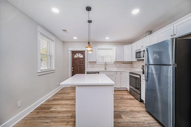 kitchen featuring a center island, a sink, white cabinetry, and appliances with stainless steel finishes