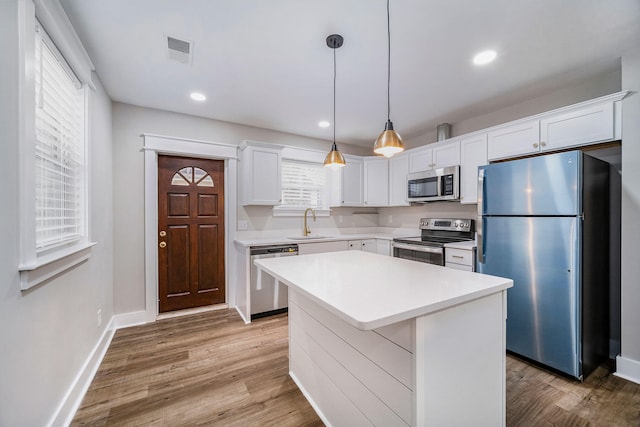 kitchen with visible vents, white cabinetry, a sink, light wood finished floors, and stainless steel appliances