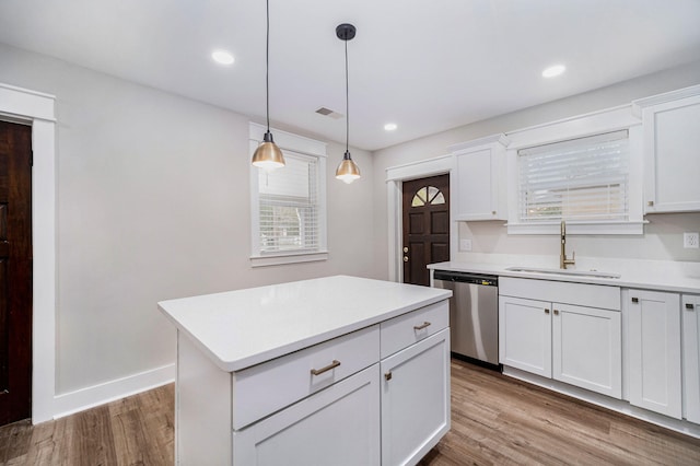 kitchen featuring stainless steel dishwasher, wood finished floors, light countertops, white cabinetry, and a sink