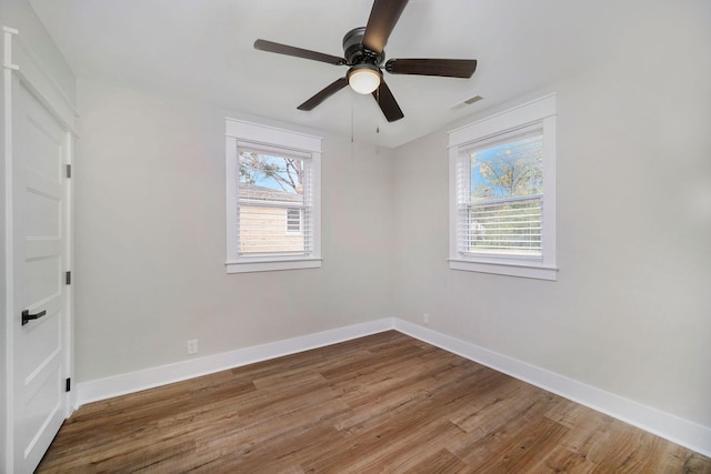 spare room featuring visible vents, baseboards, ceiling fan, and wood finished floors