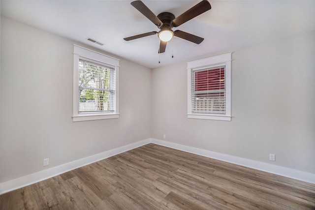 empty room with ceiling fan, baseboards, visible vents, and wood finished floors