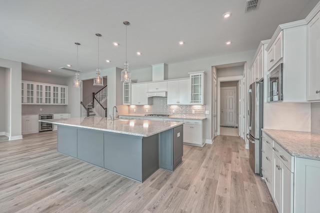 kitchen featuring a spacious island, white cabinetry, hanging light fixtures, and wine cooler