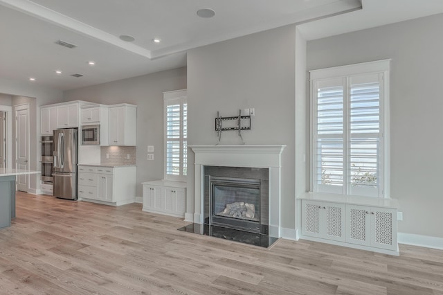 kitchen featuring stainless steel refrigerator, white cabinetry, light hardwood / wood-style floors, and built in microwave