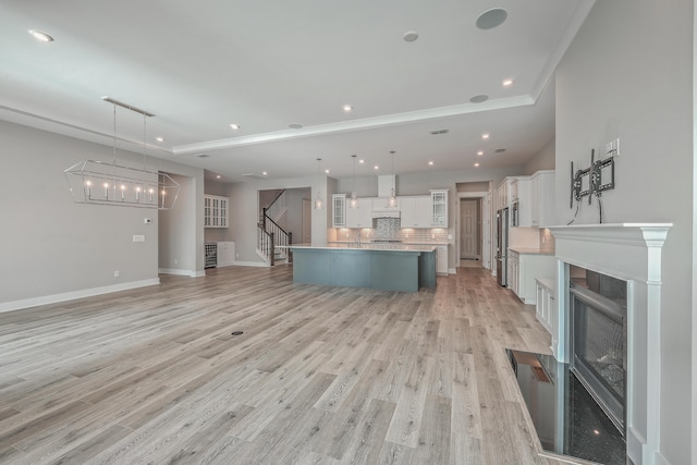 unfurnished living room with sink, a chandelier, and light hardwood / wood-style floors