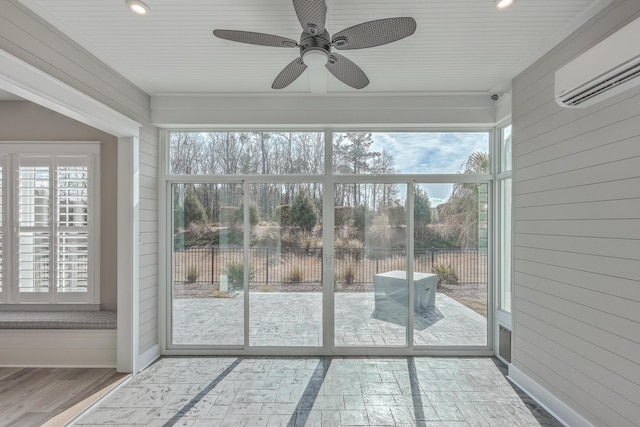 unfurnished sunroom featuring a wall mounted air conditioner and ceiling fan