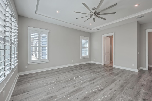 unfurnished room with ceiling fan, a tray ceiling, and light hardwood / wood-style floors