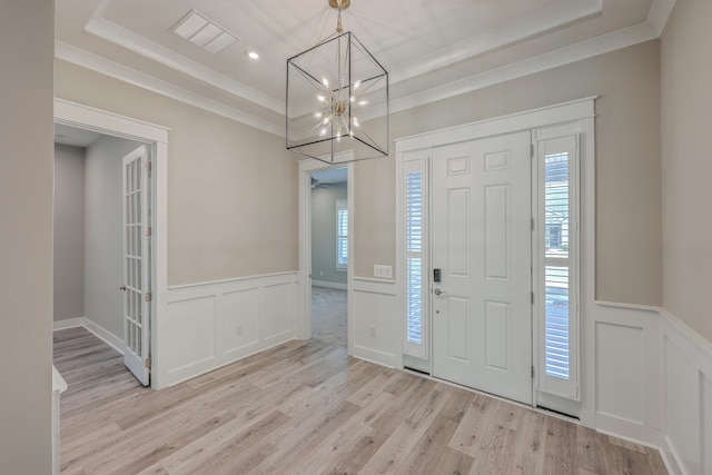 foyer with ornamental molding, a healthy amount of sunlight, and light hardwood / wood-style floors