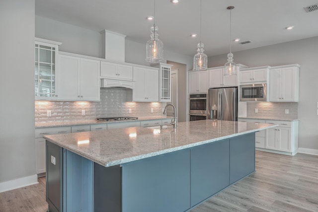 kitchen with sink, pendant lighting, stainless steel appliances, a large island, and white cabinets