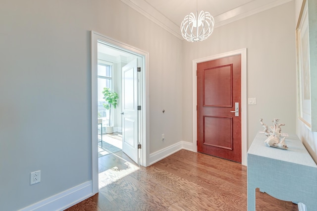 entryway with light wood-type flooring, an inviting chandelier, and ornamental molding