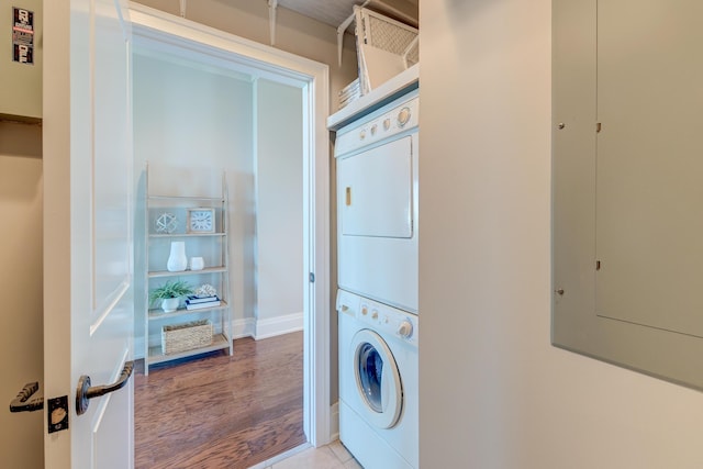 laundry room featuring electric panel, stacked washing maching and dryer, and tile patterned floors