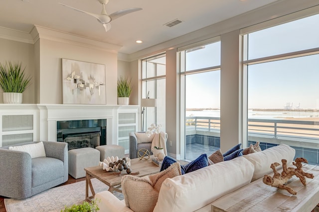 living room featuring ceiling fan, plenty of natural light, a water view, and hardwood / wood-style flooring