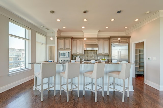 kitchen with built in appliances, decorative backsplash, a center island with sink, and pendant lighting