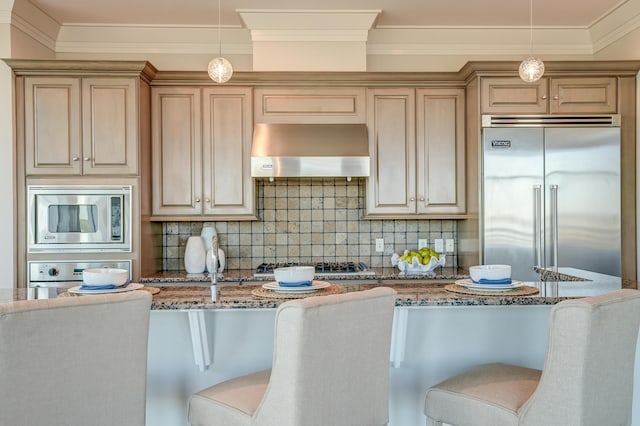 kitchen featuring light stone countertops, ventilation hood, built in appliances, pendant lighting, and a breakfast bar area