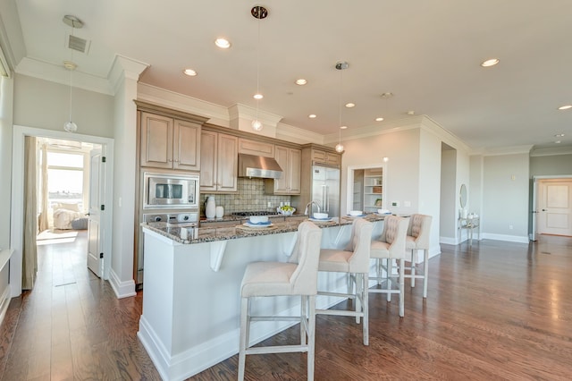 kitchen featuring decorative backsplash, light stone counters, ventilation hood, built in appliances, and hanging light fixtures